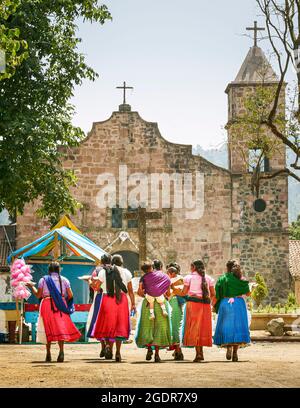Un gruppo di donne purepecha vestite di colore cammina verso il tempio della città di Capacuaro, Michoacan, Messico. Foto Stock