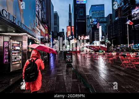 Ragazza con un ombrello rosso in una mattinata piovosa a Times Square, New York City, USA. Foto Stock