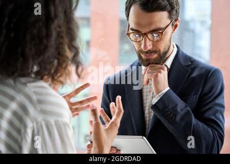 ceo esecutivo che tiene un dispositivo tablet Ascolta il manager femminile discutere del progetto. Foto Stock