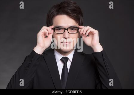 Giovane buisnessman in tuta nera e occhiali da vista Foto Stock