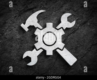 Simbolo di costruzione o manutenzione con una chiave a ingranaggi e il simbolo del martello su fondo di pietra scuro Foto Stock