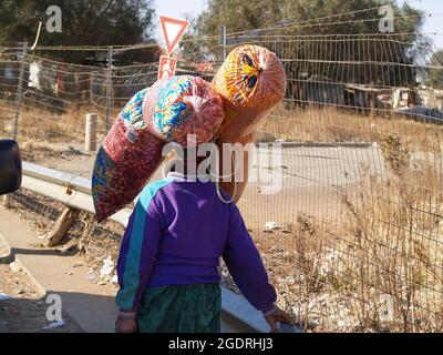 Sud Africa - Agosto 15 2007;cercando di guadagnarsi da vivere nella città povera una donna porta borse di spuntini sulla sua testa sperando di trovare un compratore a Soweto Sud A. Foto Stock