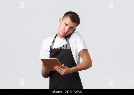 Negozi al dettaglio, piccole aziende, caffè e ristoranti concetto di takeaway. Venditore serio occupato che parla con l'azienda o il cliente di consegna, holding Foto Stock