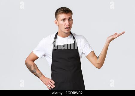 Dipendenti, negozi di alimentari e caffetteria. Cameriere deluso e infastidito, barista che punta a destra e che guarda dispiaciuto, lamentandosi Foto Stock