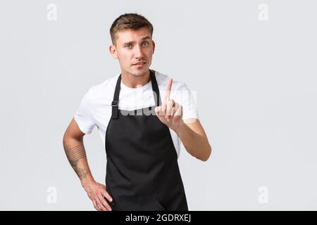 Dipendenti, negozi di alimentari e caffetteria. Un barista dall'aspetto serio insegna come preparare il caffè a casa, scuotendo il dito come scolding Foto Stock