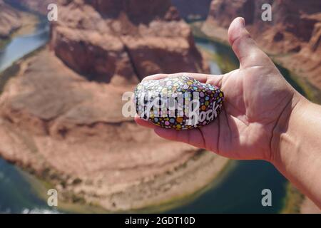 Il rock di gentilezza che dice che il rock è tenuto in mano sopra Horseshoe Bend Foto Stock