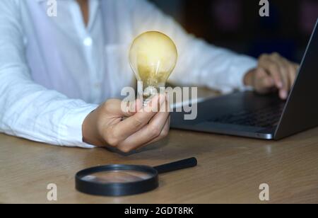 Concetto astratto di lampadina e lente d'ingrandimento gli uomini d'affari mostrano nuove idee utilizzando la tecnologia innovativa e la creatività. Foto Stock