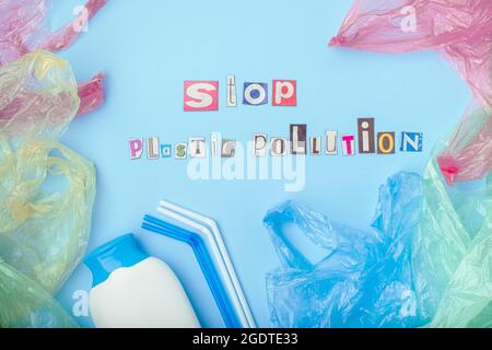 Fermare le parole di inquinamento di plastica tagliate fuori dai caricatori. Disposizione piatta, su sfondo blu. Vista dall'alto. Foto di alta qualità Foto Stock