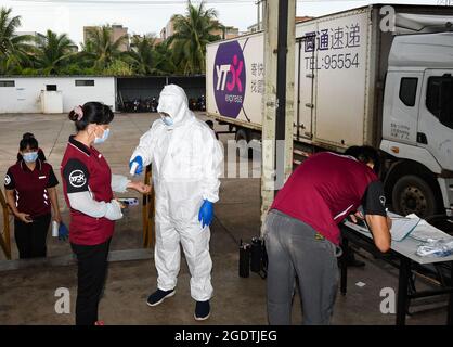 Haikou, provincia cinese di Hainan. 15 agosto 2021. I membri del personale ricevono un controllo della temperatura corporea prima di lavorare in un centro di trasporto a Haikou, nella provincia di Hainan, nella Cina meridionale, il 15 agosto 2021. Credit: Yang Guanyu/Xinhua/Alamy Live News Foto Stock