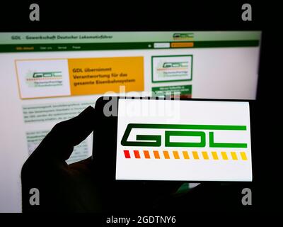 Persona che detiene il telefono cellulare con il logo di Union Gewerkschaft Deutscher Lokomotivfuehrer (GDL) sullo schermo davanti alla pagina web. Mettere a fuoco il display del telefono. Foto Stock