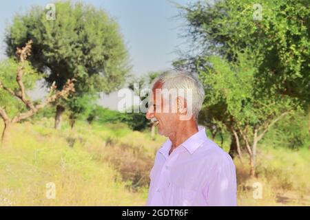 Primo piano vista del profilo ritratto di un uomo anziano indiano che posa fuori della natura Foto Stock