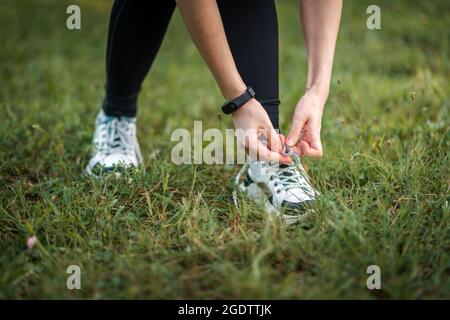 Donna in abiti sportivi che legano scarpe da ginnastica. Primo piano con smartwatch e scarpe. Concetto di fitness. Foto Stock