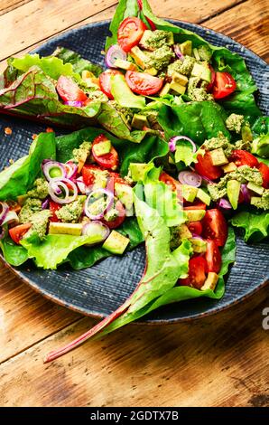 Insalata di avocado, pomodoro con salsa all'aglio in foglie di bietole. Insalata di vitamina estiva in piatto Foto Stock