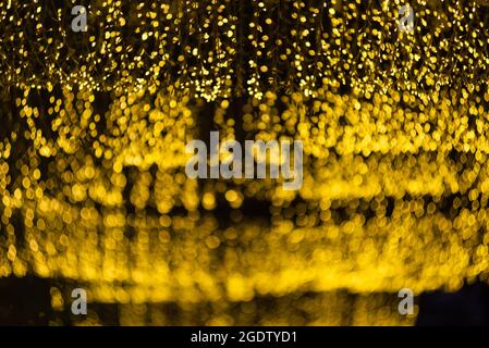 molti dei bokeh dal tubo della lampadina chiaro su una strada di notte che assomiglia alla luce della stella dorata di lusso in sfondo scuro Foto Stock