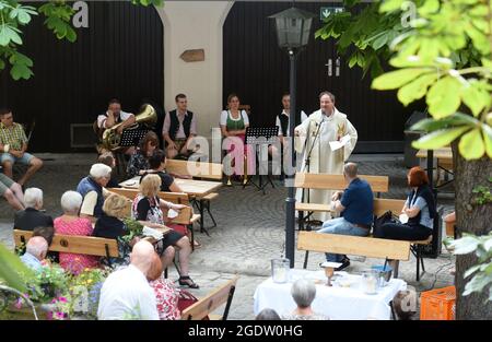 Monaco, Germania. 15 agosto 2021. Padre Rainer Maria Schießler ha una Santa messa nel cortile della Hofbräuhaus di fronte a numerosi visitatori come parte di un servizio all'aperto. L'amianto deve essere rimosso dalla chiesa di San Massimiliano nel Glockenbachviertel, quindi l'edificio non sarà utilizzabile per nove mesi. Durante questo periodo, Padre Schießler predicherà, per esempio, sul Nockherberg, nel Hofbräuhaus, nel Vecchio Municipio, nel ricovero degli animali e sul Theresienwiese. Credit: Felix Hörhager/dpa/Alamy Live News Foto Stock