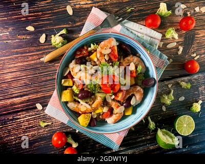 Insalata fresca di gamberi al vapore, cavolo, avocado, spinaci, pomodori ciliegini, broccoli, lattuga, anacardi, sedano, mango, olive Foto Stock