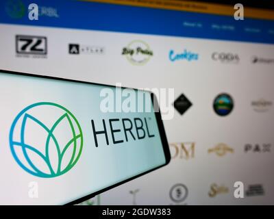 Telefono cellulare con logo della società americana di fornitura di cannabis HERBL sullo schermo di fronte al sito web aziendale. Mettere a fuoco al centro-sinistra del display del telefono. Foto Stock