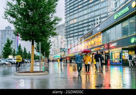 Persone che camminano in via Noviy Arbat sotto la pioggia, sera, Mosca, Russia Foto Stock