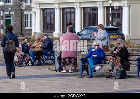 La gente sedette bevendo bevande avvolte in una fredda mattina di primavera Foto Stock