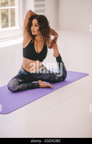 Donna che fa yoga asana in classe fitness. Donna sportiva che pratica yoga, facendo una zampe di porcione re al centro benessere. Foto Stock