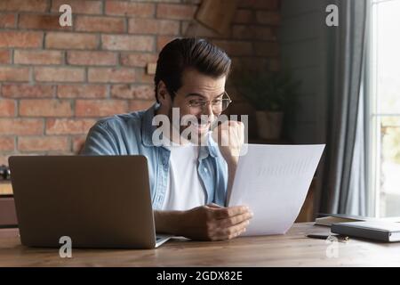 L'uomo caucasico eccitato si sente euforico con le notizie nella lettera Foto Stock