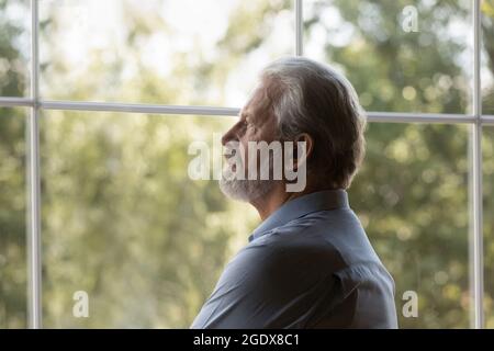 L'uomo anziano sconvolto guarda a distanza sentendosi triste Foto Stock