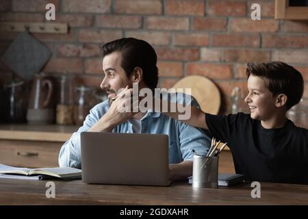 Piccolo figlio teen distrarre papà dal lavoro a casa Foto Stock