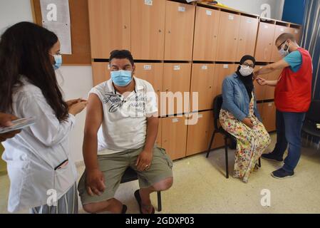 Tunisi, Tunisia. 15 agosto 2021. Gli operatori sanitari somministrano dosi di vaccino Moderna COVID-19 alle persone in un centro di inoculazione in un edificio delle scuole superiori nella capitale Tunisi. Il Direttore Generale della Sanità tunisina Faycel ben Salah ha detto che circa 1 milione di persone sarà chiamato al 2° giorno di vaccinazione intensiva del coronavirus, che si rivolge ai gruppi di 18-39 anni. Credit: SOPA Images Limited/Alamy Live News Foto Stock