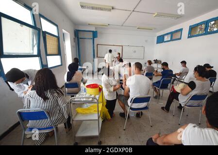 Tunisi, Tunisia. 15 agosto 2021. Gli operatori sanitari somministrano dosi di vaccino Moderna COVID-19 alle persone in un centro di inoculazione in un edificio delle scuole superiori nella capitale Tunisi. Il Direttore Generale della Sanità tunisina Faycel ben Salah ha detto che circa 1 milione di persone sarà chiamato al 2° giorno di vaccinazione intensiva del coronavirus, che si rivolge ai gruppi di 18-39 anni. Credit: SOPA Images Limited/Alamy Live News Foto Stock