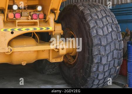 Pneumatico a ruota gigante di un enorme dumper da miniera industriale nella stazione di riparazione. Ruota del dumper automatico giallo dopo la sostituzione degli pneumatici. Foto Stock