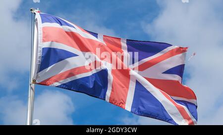 Una bandiera Union Jack che vola da un palo di bandiera nel cielo, la bandiera nazionale del Regno Unito di Gran Bretagna Foto Stock