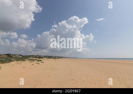 Vista sulla splendida spiaggia di Mazagon, situato nella provincia di Huelva, Spagna. Con le sue scogliere, pini, dune, vegetazione verde e nuvole Foto Stock