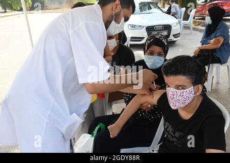 Tunisi, Tunisia. 15 agosto 2021. Un operatore medico somministra una dose di vaccino COVID-19 ad un ricevente in un centro di vaccinazione a Tunisi, Tunisia, 15 agosto 2021. La seconda giornata nazionale tunisina aperta per la vaccinazione contro la COVID-19 è iniziata domenica in tutte le 24 province del paese per i cittadini di età compresa tra i 18 e i 39 anni. In tutto 405 centri di vaccinazione, distribuiti in tutto il paese, sono stati allestiti esclusivamente per questa giornata aperta. Credit: Adel Ezzine/Xinhua/Alamy Live News Foto Stock