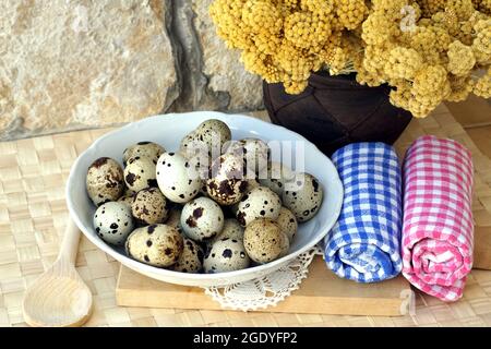 Uova di quaglia giapponese in un'esposizione rustica con fiori immortelle in un vaso. Sfondo di cibo rurale Foto Stock