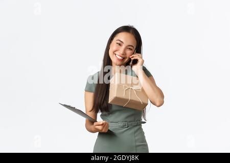 Amichevole sorridente e gentile proprietario asiatico negozio femminile, la gestione di piccole imprese, portare appunti e confezione per la spedizione, rispondere clienti chiamata Foto Stock