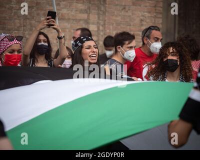 Le ragazze arabe con maschere chirurgiche sui loro volti scuotono una grande bandiera durante un incontro politico. Foto Stock