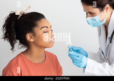 Medico che prende il tampone nasale per il campione di coronavirus da paziente femminile Foto Stock