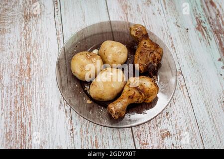 due cosce di pollo grigliate e patate sul piatto Foto Stock