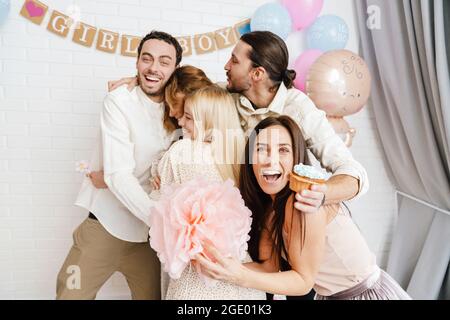 Giovane coppia entusiasta che si agguanata con i loro amici durante la festa di genere rivela all'interno Foto Stock