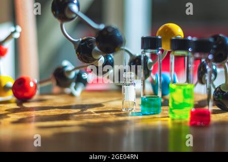 Soluzioni di composti chimici in diverse fiale di vetro sotto la luce con modello molecolare in un laboratorio chimico per la ricerca sanitaria Foto Stock