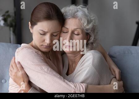 Amorevole figlia abbraccio e conforto vecchia mamma sconvolta Foto Stock