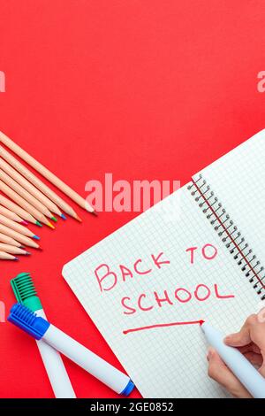 Ritorno a scuola. Il bambino scrive di nuovo a scuola in un notebook in un pennarello rosso. Il concetto di inizio dell'anno scolastico. Banner per il sito su un Foto Stock