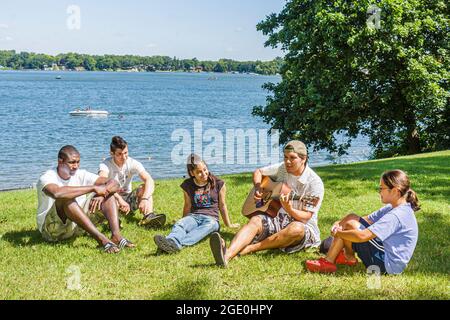 Wisconsin Kenosha Paddock Lake, Old Settlers Park Ispanico Nero adolescenti, ragazze ragazzi maschi suonare la chitarra ascoltare gruppo rilassarsi, Foto Stock