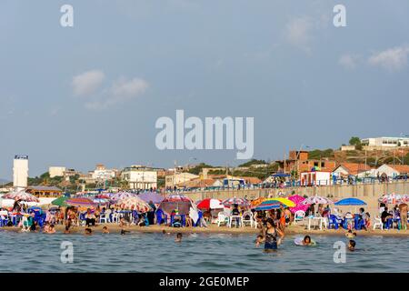 Vista ad angolo basso delle famiglie che si divertono sulla spiaggia, i bambini che giocano in acqua, Skikda, Algeria. Foto Stock