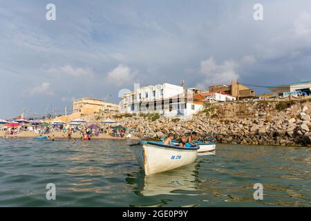 Vista ad angolo basso di due bambini che si divertono all'interno di una barca da pesca sulla spiaggia. Foto Stock