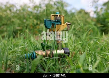 Sistema di innaffiatura in metallo su fondo verde erba closeup Foto Stock