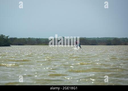 Riohacha, la Guajira, Colombia - Maggio 30 2021: Il giovane uomo Nero organizza la sua rete di pesca nella Riserva Naturale Foto Stock