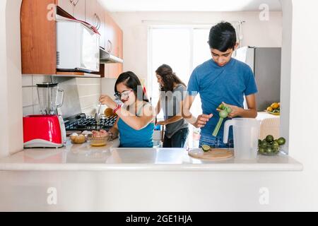 Ragazza teenage messicana con sindrome di Down con la sua famiglia che cucina in cucina a casa, in concetto di disabilità in America Latina Foto Stock