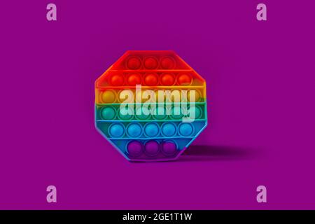 Il fidget giocattolo in silicone ottagonale lo schioccano su sfondo viola Foto Stock