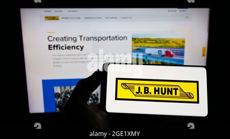 Persona che detiene smartphone con il logo della società logistica J.B. Hunt Transport Services Inc. Sullo schermo davanti al sito Web. Mettere a fuoco il display del telefono. Foto Stock